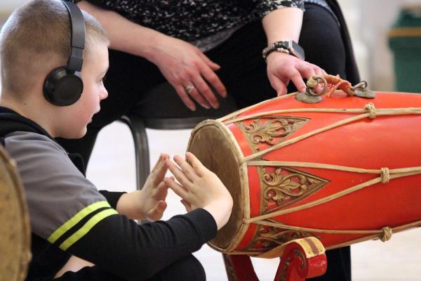 A boy sits and plays a drum from Java