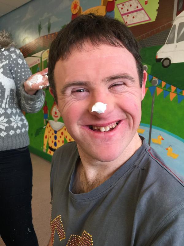 A man smiles at the camera with a white blob of paint on his nose