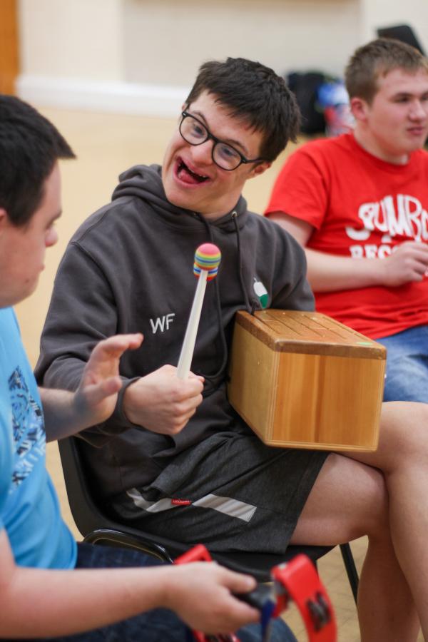 IMPs member smiling and playing a wooden block