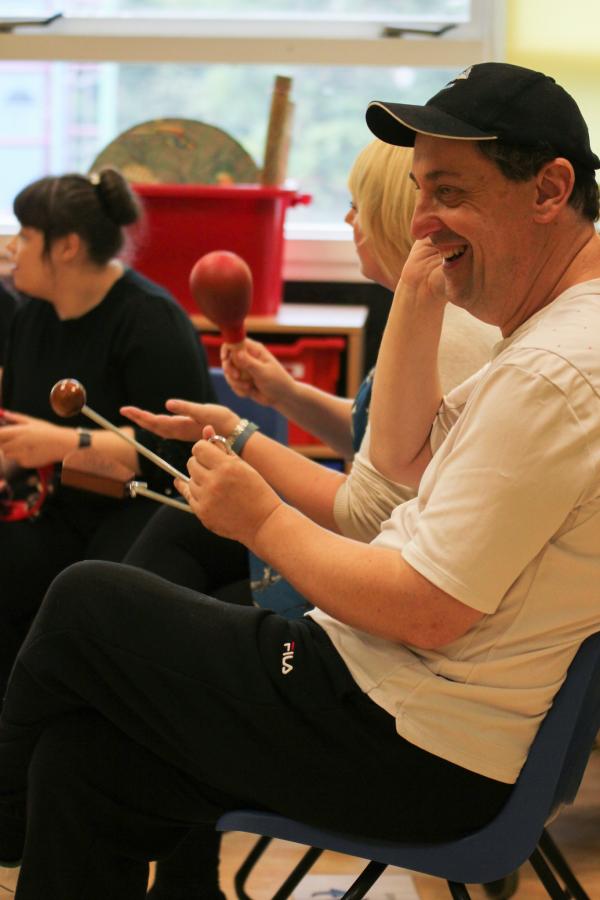 Music member participant is playing an instrument and smiling