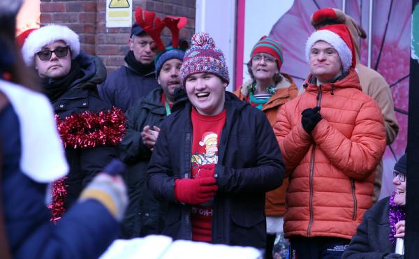 Singers gather together in coats, wooly hats and tinsel to sing Christmas Carols