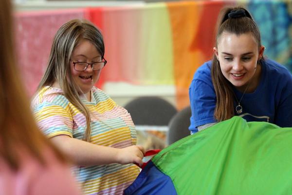 Two people smile as they hold a parachute that represents a volcano