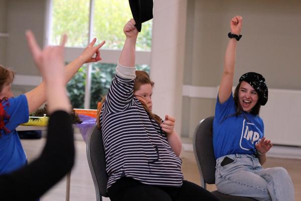 A group of people raise their hands as they introduce each person to the group