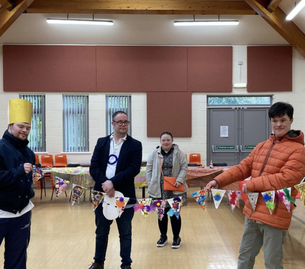 Four people stand together showing bunting they have decorated