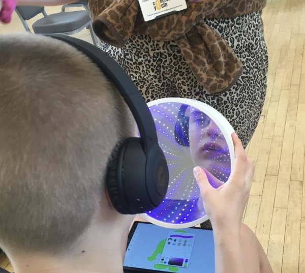 A boy looks into an infinity mirror where his face is reflected
