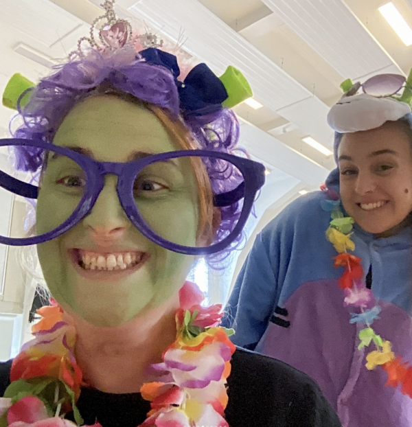 A lady wears green facepaint and big glasses with ogre ears