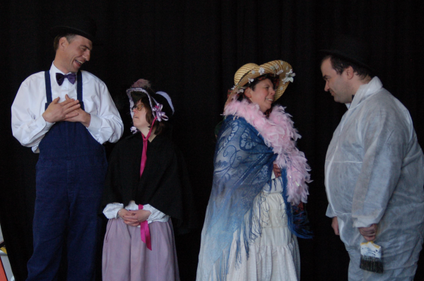 Four performers stand on stage, dressed in period clothing